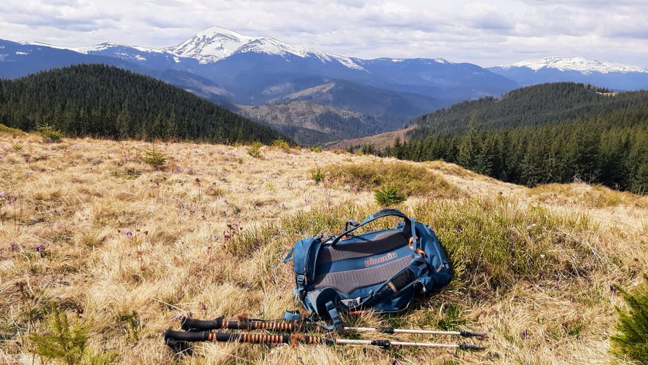 Serene view of the Carpathian Mountains with a backpack and hiking poles in the foreground.