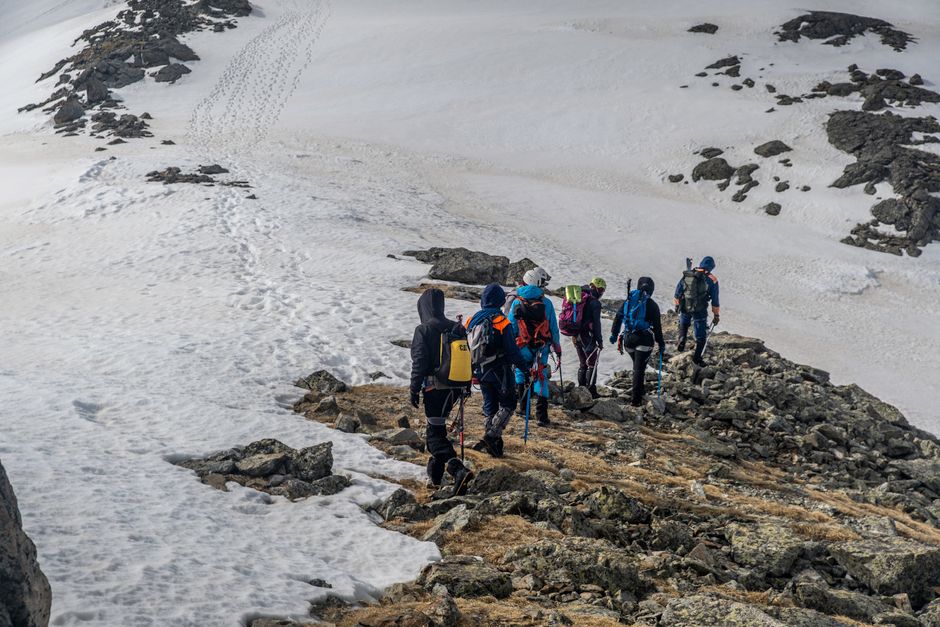 Adventurous group hiking on a snowy mountain ridge during winter, showcasing teamwork.