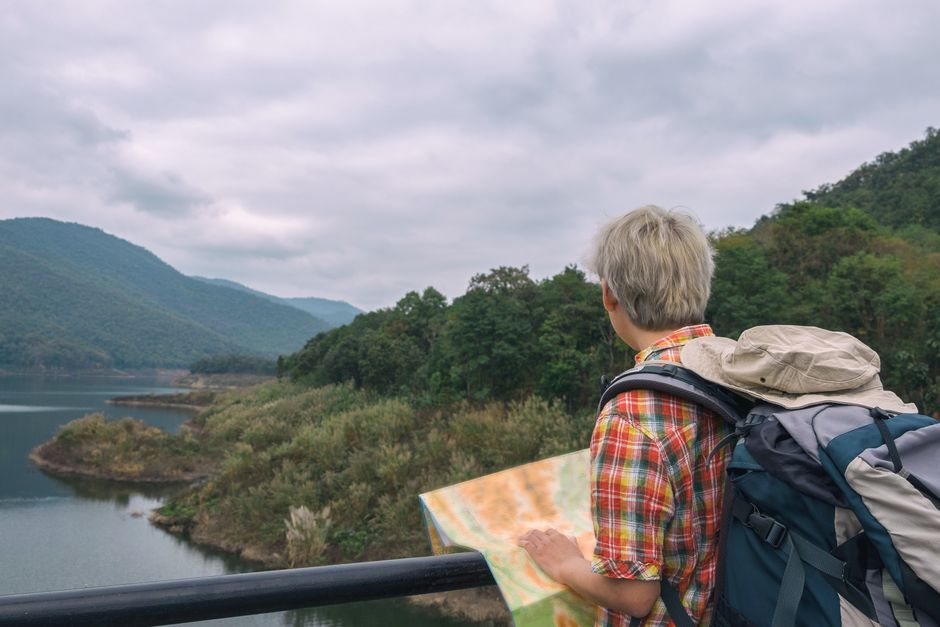 Traveler with backpack and map exploring picturesque mountain landscape.