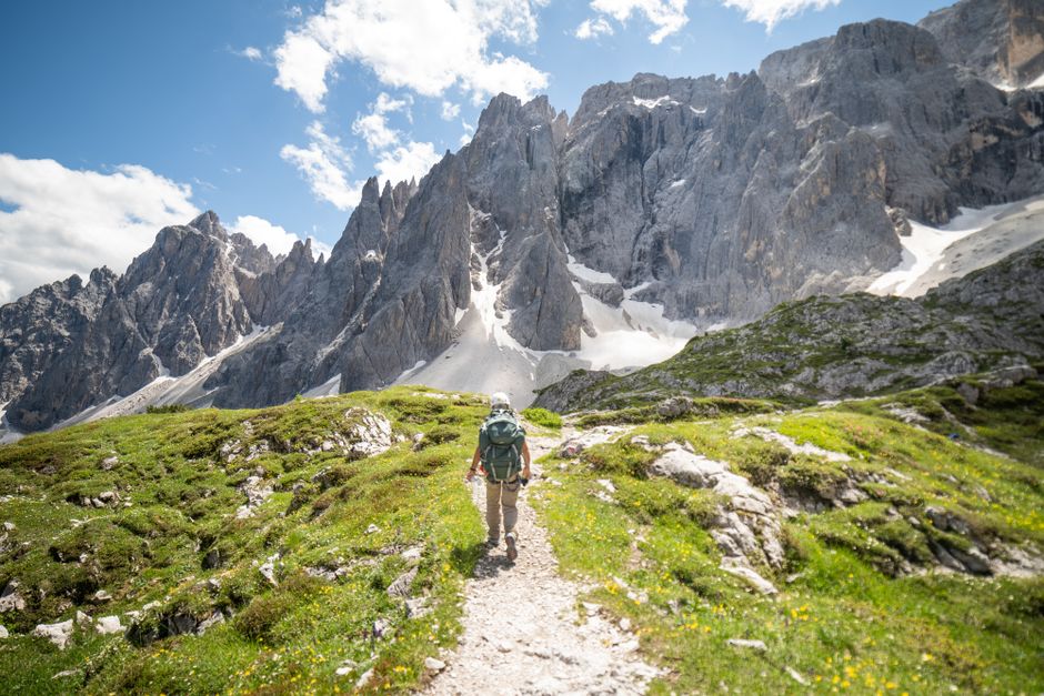 A hiker ventures through the stunning Dolomite Mountains in Bolzano, Italy on a bright summer day.